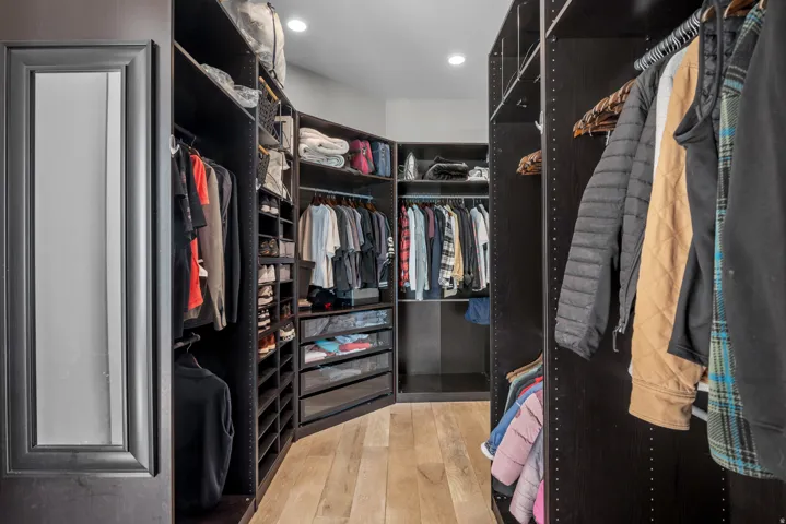 Custom closet system featuring dark wood-finish cabinetry, integrated shelving, hanging rods, and built-in drawers