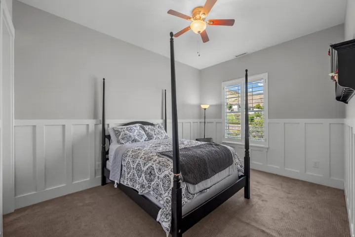 Vaulted ceiling with a ceiling fan, board and batten wainscoting, and carpeted flooring