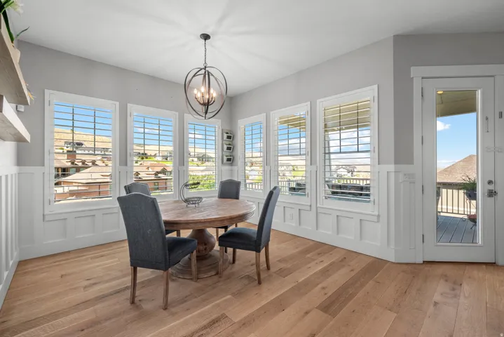 Hardwood flooring, wainscoting, multiple windows with plantation shutters, patio access, and an orb chandelier