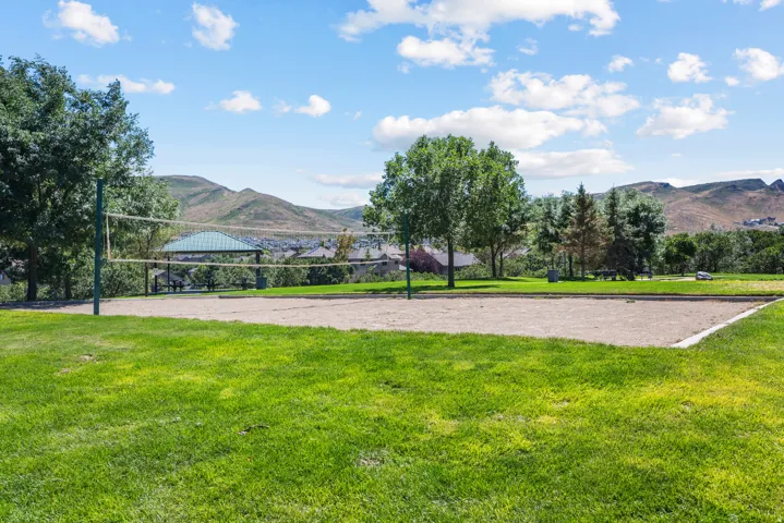 Expansive green space featuring a sand volleyball court