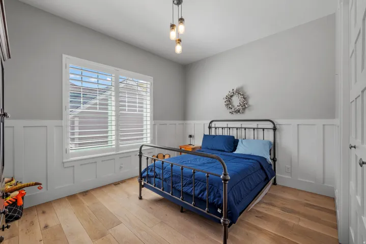 Hardwood-finish flooring, white wainscoting, and a white paneled door