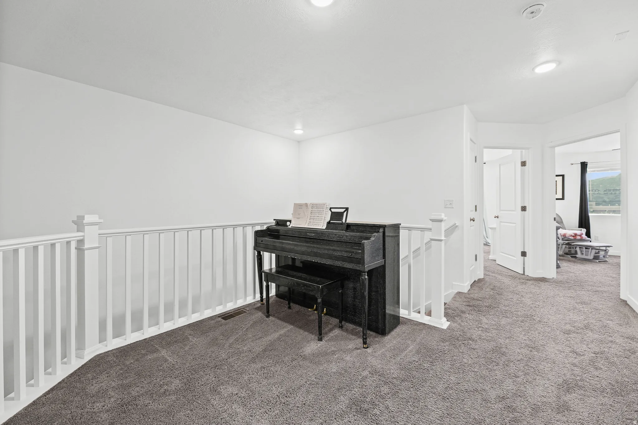 Carpeted hallway with white railing and neutral wall paint