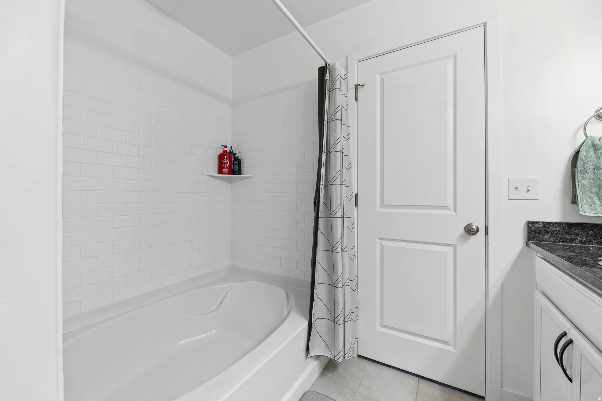 Tub-shower combination with white subway tile surround and integrated corner shelf