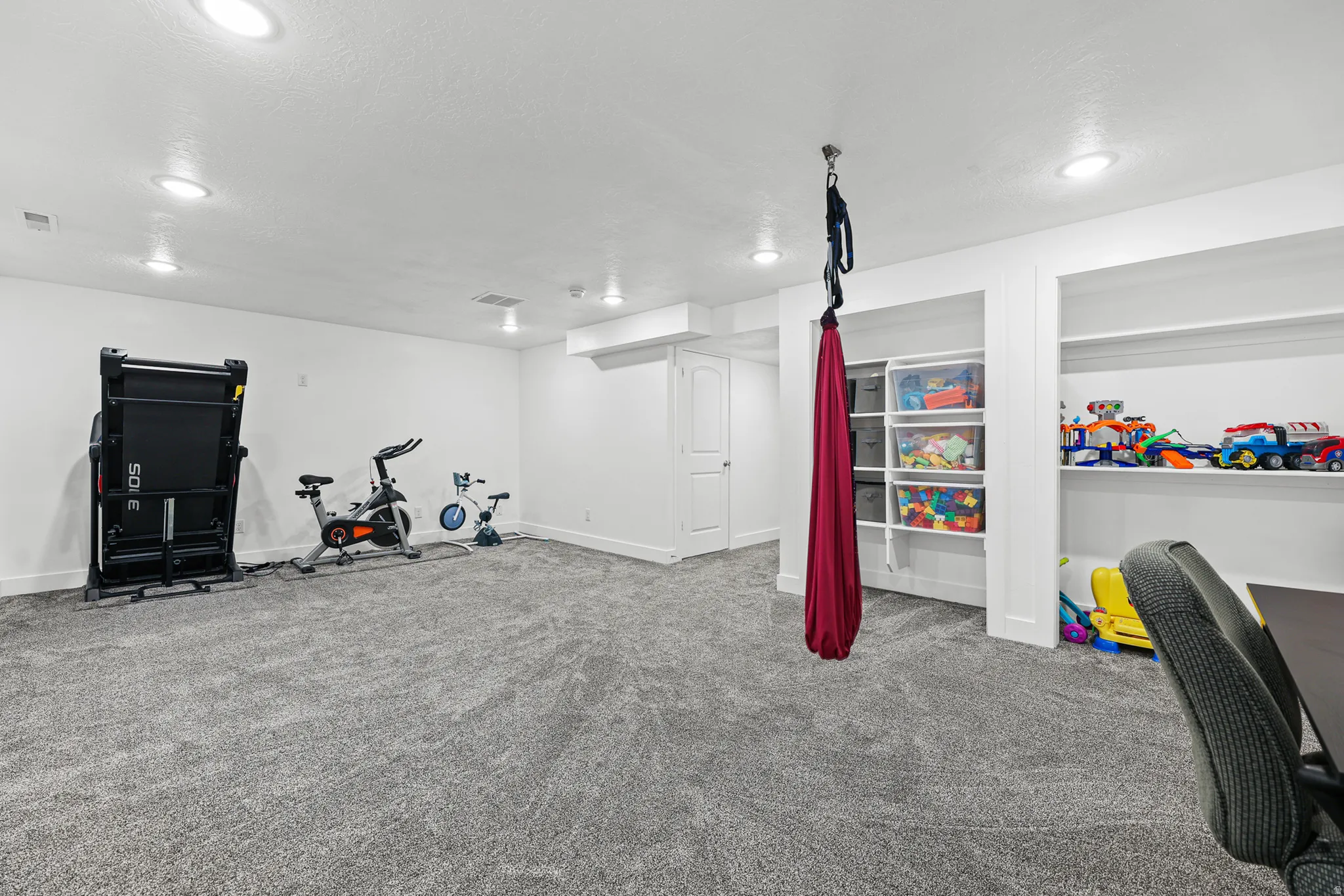 Spacious room featuring neutral carpeting, recessed lighting, and built-in shelving units
