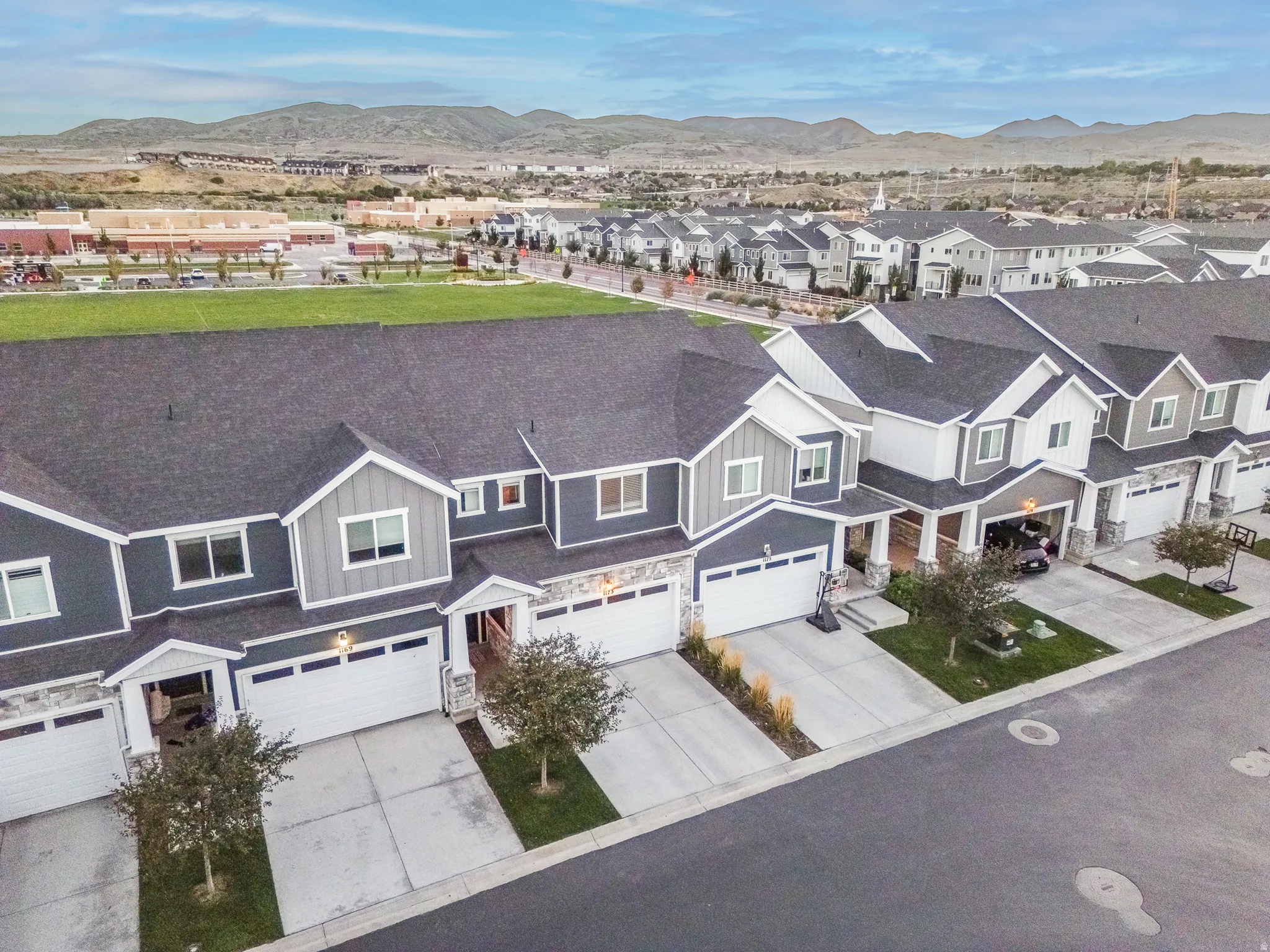 Contemporary townhome exterior with dark gray siding, light gray gables, and white garage doors