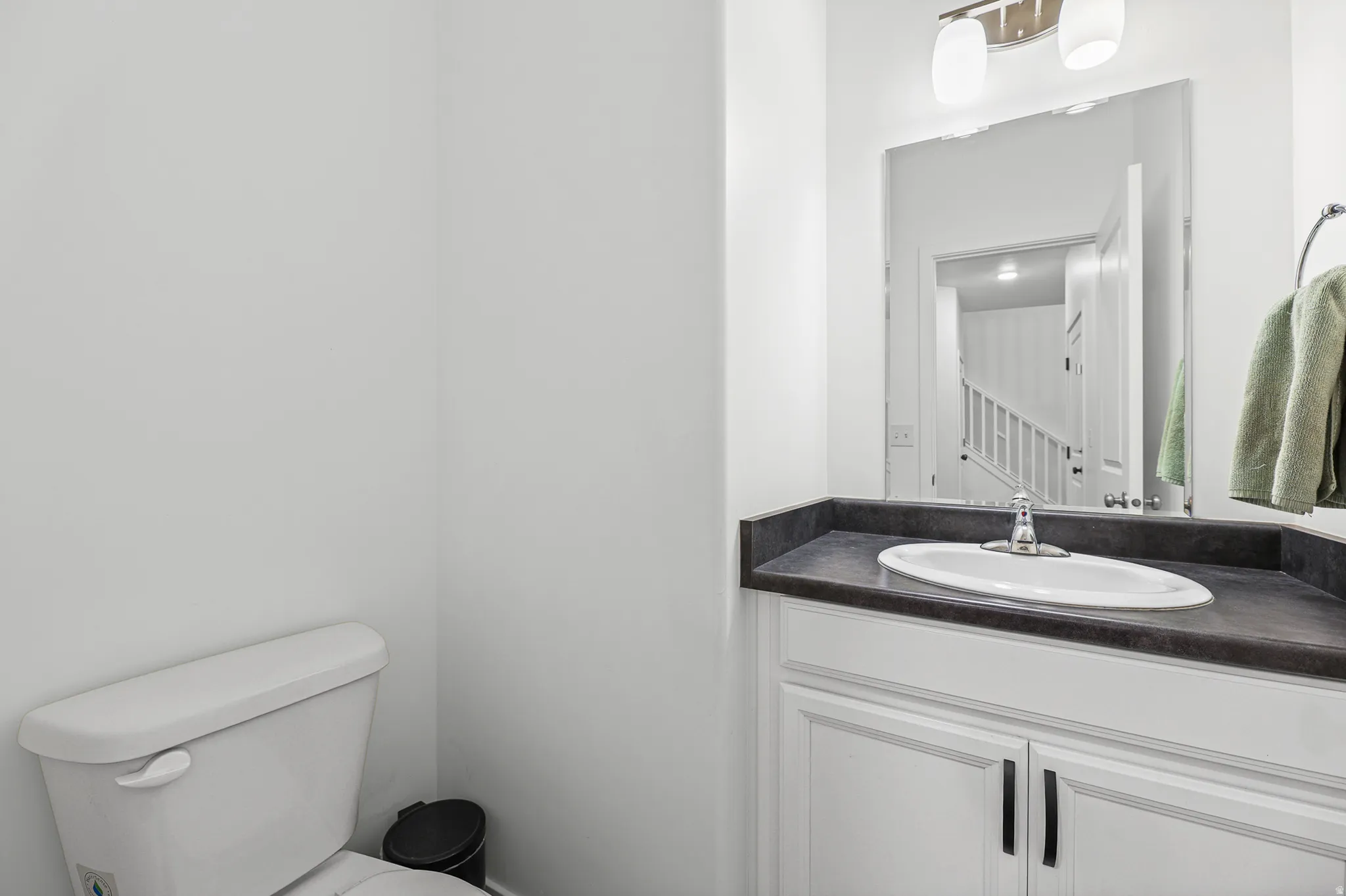 White vanity with shaker-style cabinetry, dark countertop, and an undermount sink