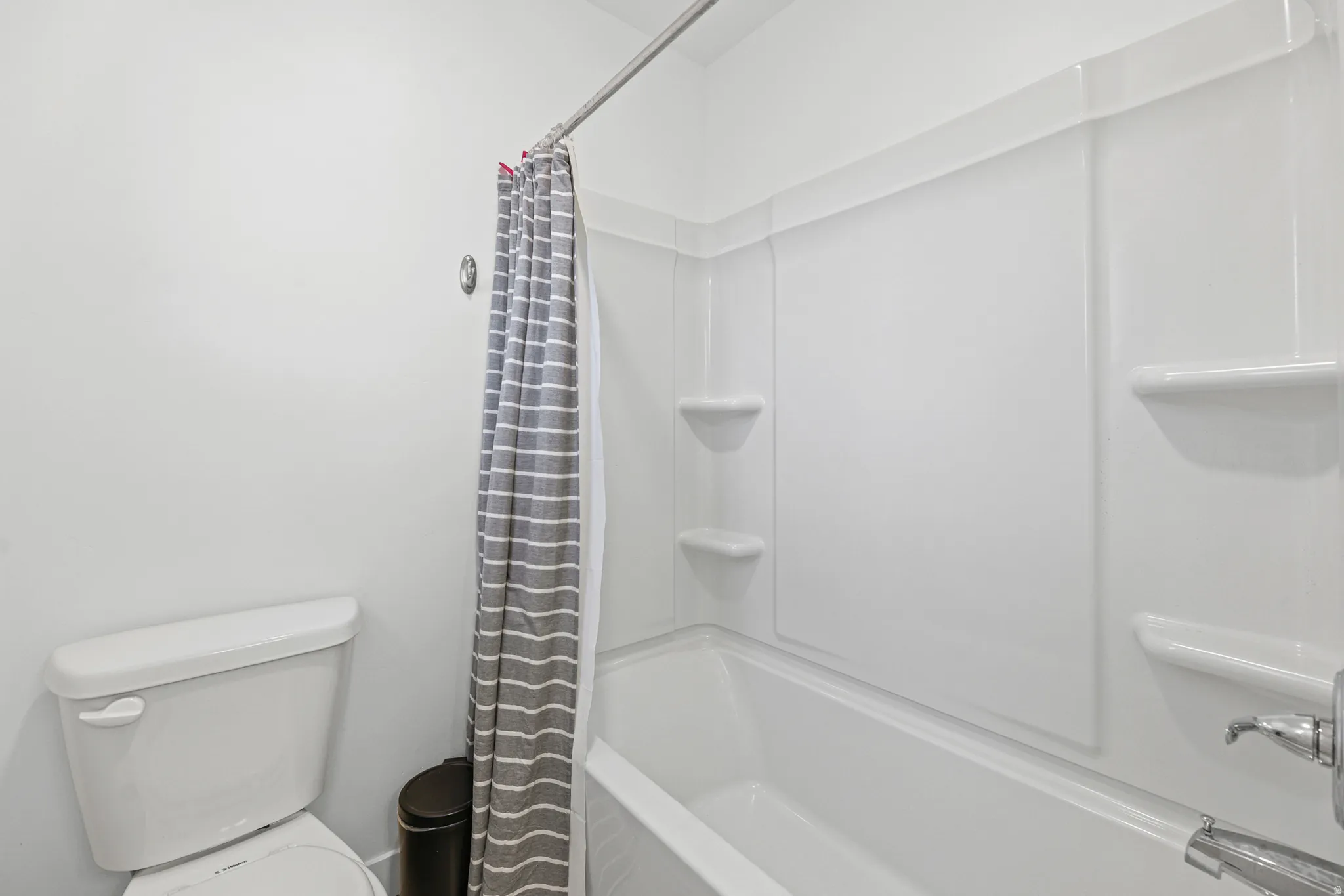 White wall-mounted shower-tub combination featuring integrated shelving