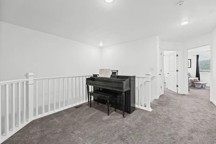 Carpeted hallway with white railing and neutral wall paint