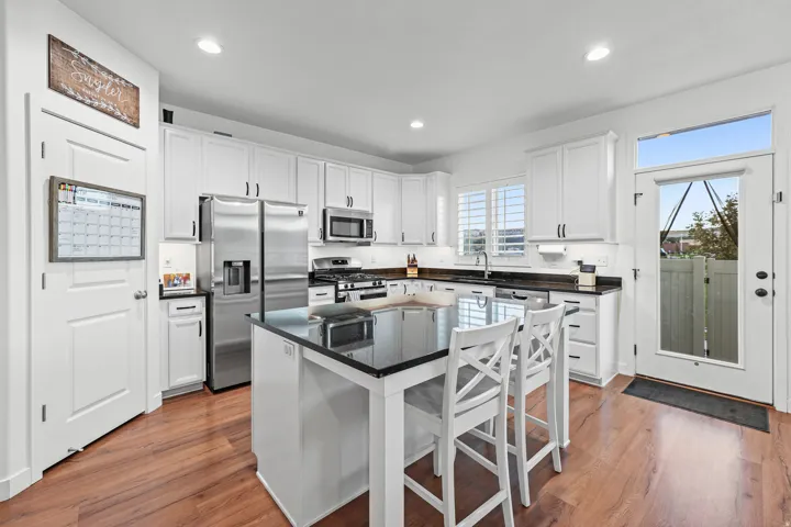 Kitchen featuring white cabinetry, dark countertops, stainless steel appliances, a center island, and wood-finish flooring
