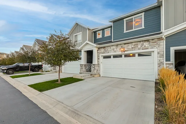 Two-story exterior with horizontal siding and stacked stone accents, a two-car garage with transom windows, and a concrete driveway