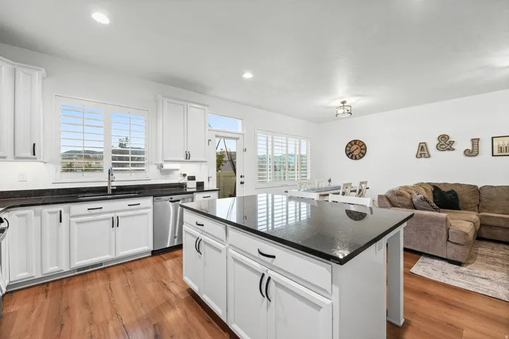 Spacious kitchen featuring white cabinetry, dark countertops, wood-finish flooring, and a central island