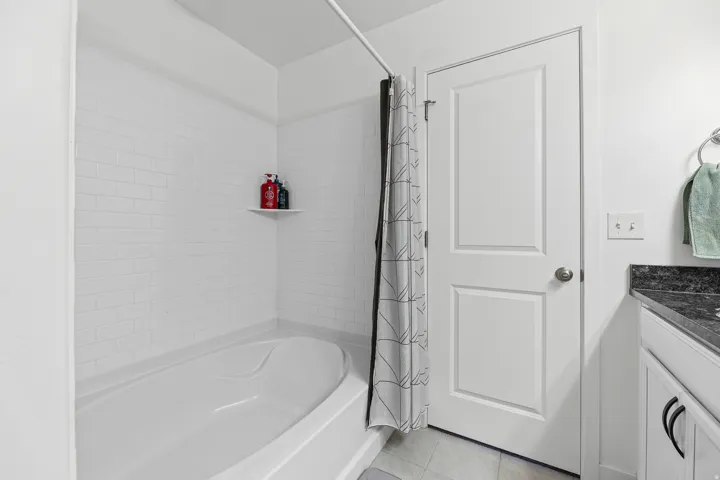 Tub-shower combination with white subway tile surround and integrated corner shelf