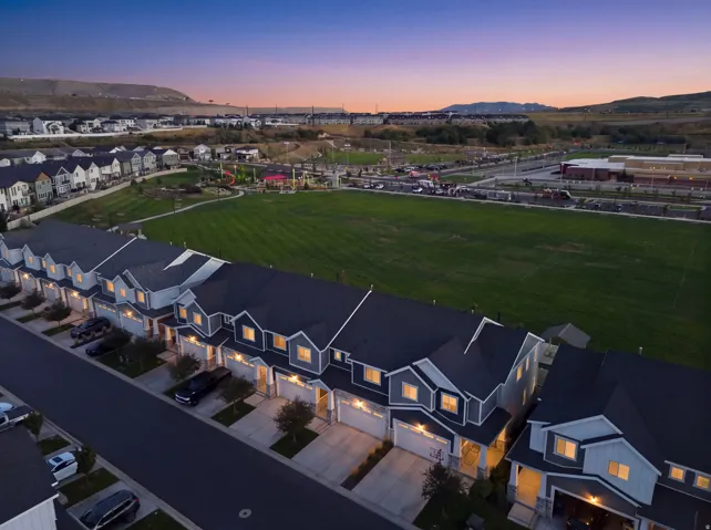 Townhome community with attached garages, manicured green space, and distant mountain scenery