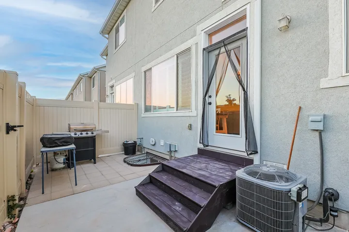 Patio area featuring a privacy fence, concrete and paver flooring, exterior door with a screen, and a multi-level wood deck