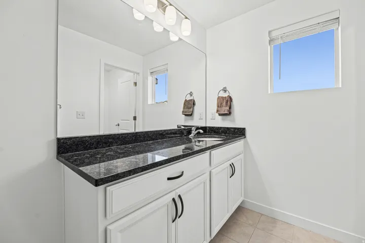 White vanity with dark stone countertop and integrated sink