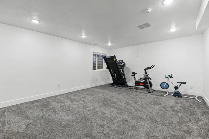White walls, recessed lighting, and a single window with blinds