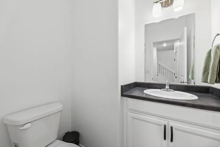 White vanity with shaker-style cabinetry, dark countertop, and an undermount sink