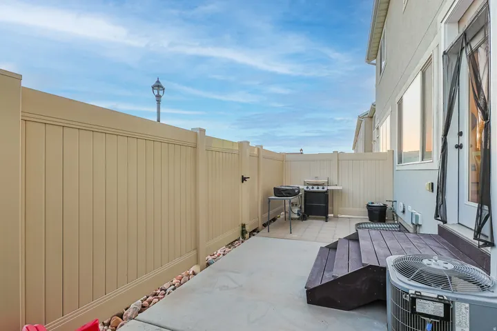 Private patio area featuring a composite deck, concrete pad, and vinyl fencing