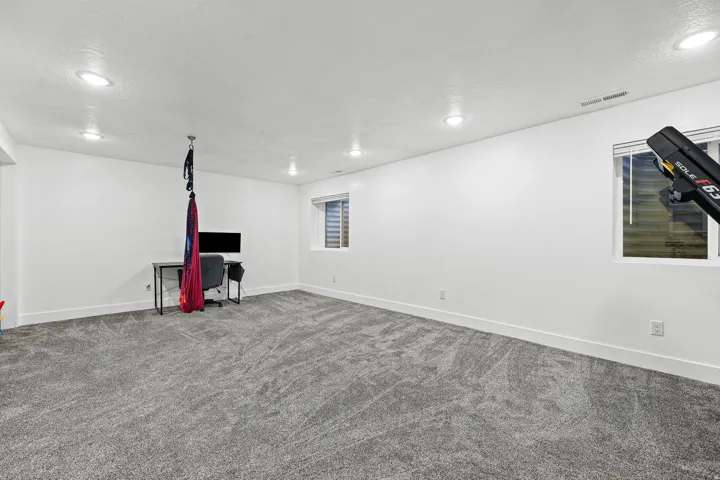 Spacious room featuring neutral carpeting, recessed lighting, and multiple windows