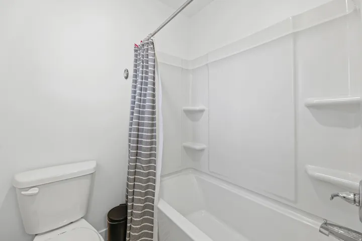 White wall-mounted shower-tub combination featuring integrated shelving