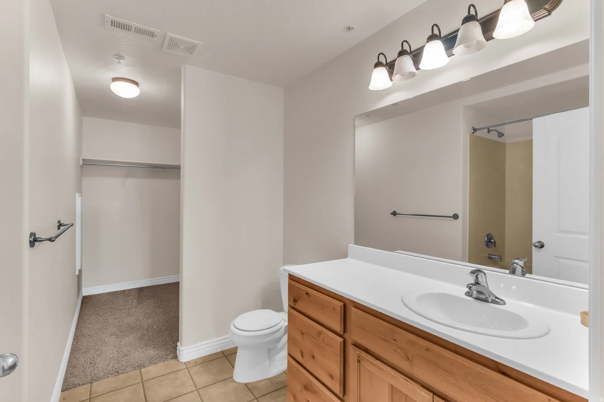 Bathroom featuring a wood-finish vanity with an integrated sink and a large mirror