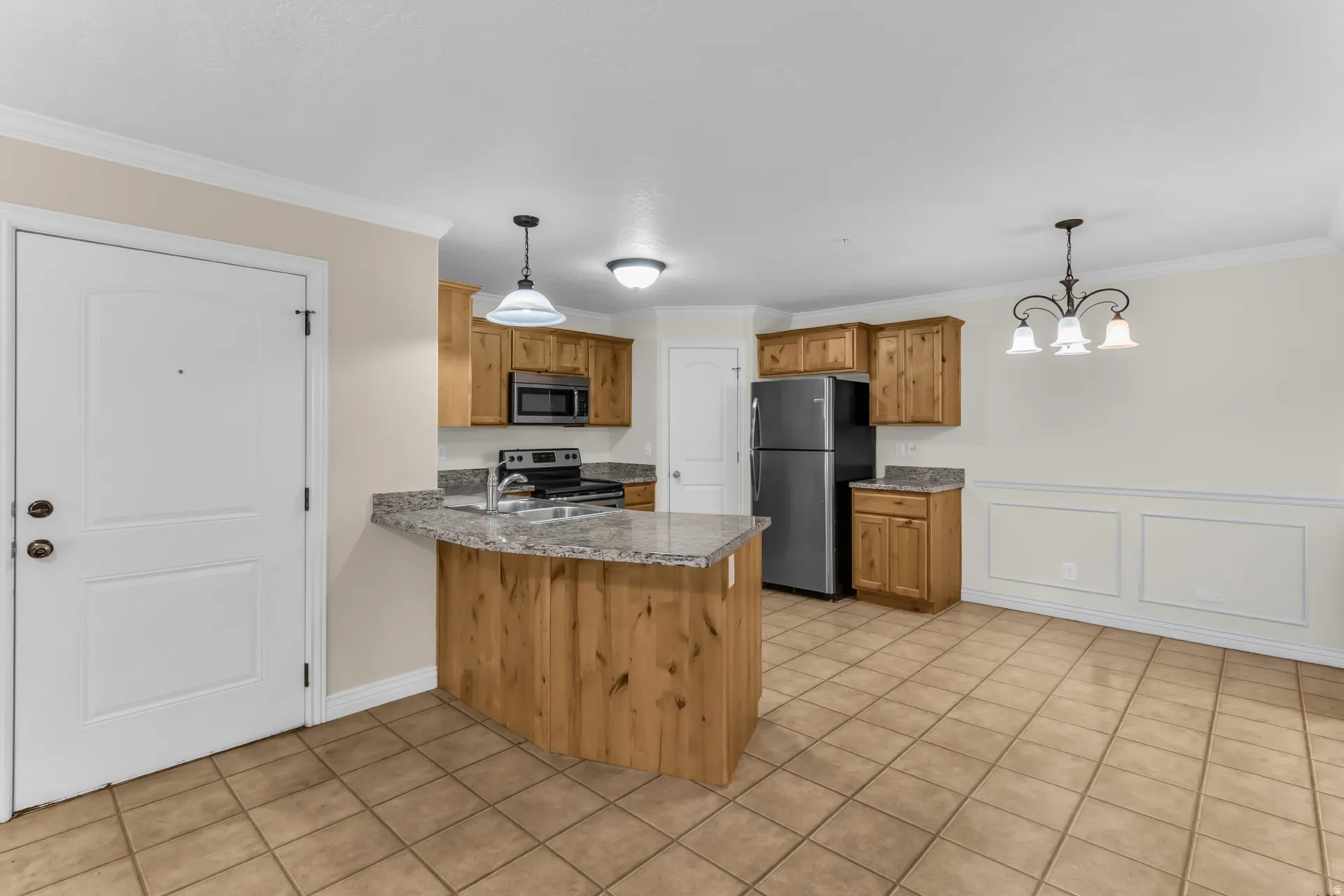 Kitchen and dining area featuring a breakfast bar, stainless steel appliances, wood-finish cabinetry, and tile flooring