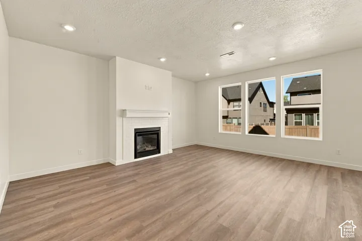 Living area featuring wood-finish flooring, recessed lighting, and a fireplace with a white brick surround and mantle