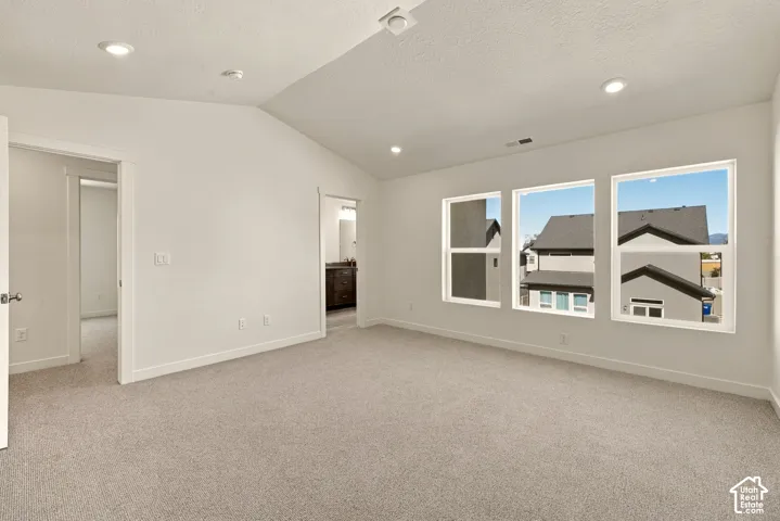 Vaulted ceiling with recessed lighting, neutral wall-to-wall carpeting, and triple-pane window configuration