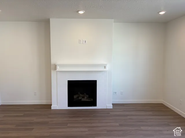 Recessed lighting, a fireplace with a white tile surround, a classic white mantel, and wood-finish flooring