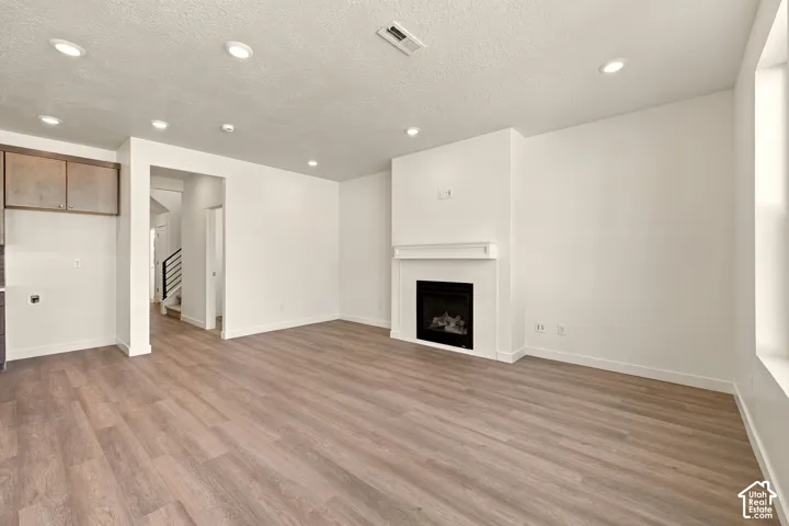 Living area featuring wood-finish flooring, recessed lighting, and a fireplace with a mantel