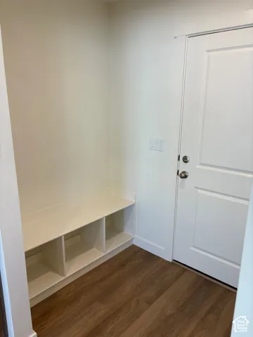 Built-in storage bench with cubbies, wood-finish flooring, and a white paneled door with brushed nickel hardware