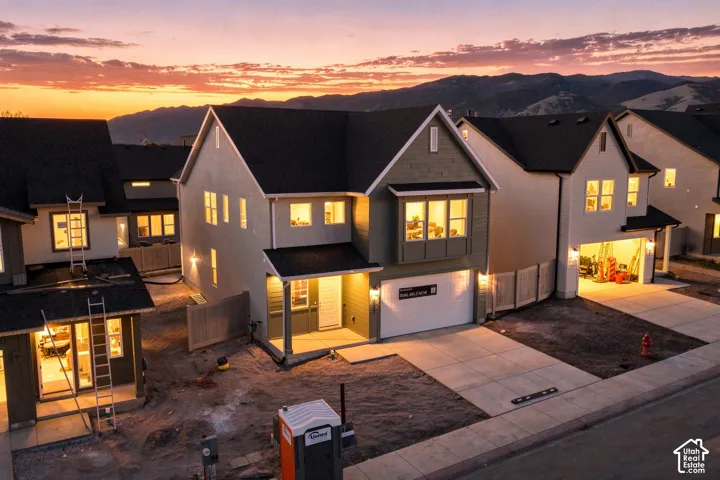 Two-story residence featuring horizontal lap siding, a front-facing gable, a concrete driveway, and an attached two-car garage, set against a mountain backdrop