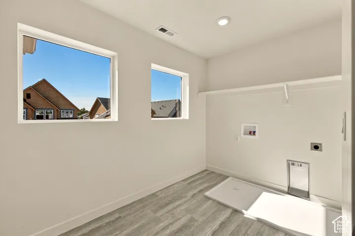 Laundry area featuring wood-finish flooring, dual windows, recessed lighting, and a built-in wall shelf