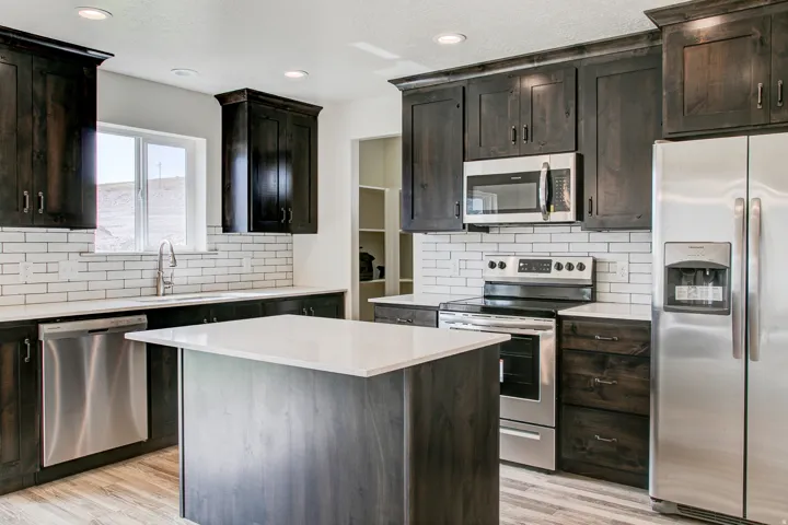 Kitchen featuring dark wood-finish cabinetry, stainless steel appliances, a center island with a white countertop, and a white subway tile backsplash