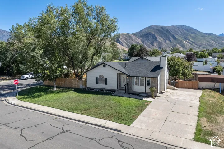 Mountain backdrop, mature trees, front lawn, paved RV driveway, privacy fencing