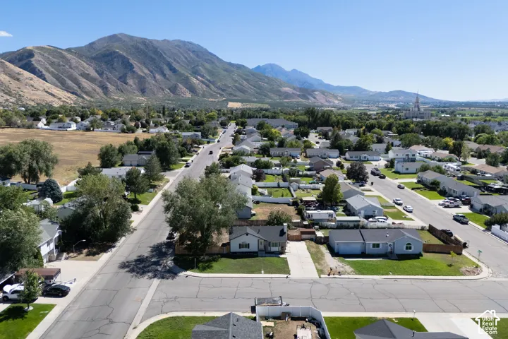 Residential neighborhood with mature trees, mountain backdrop, and distant steeple