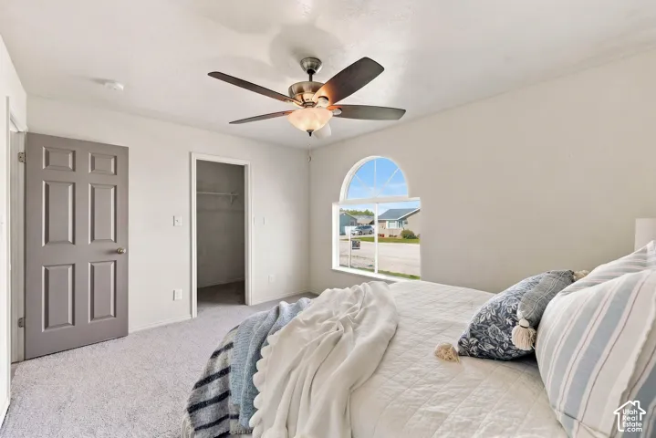 Light-toned walls with a ceiling fan, arched window, and gray paneled door