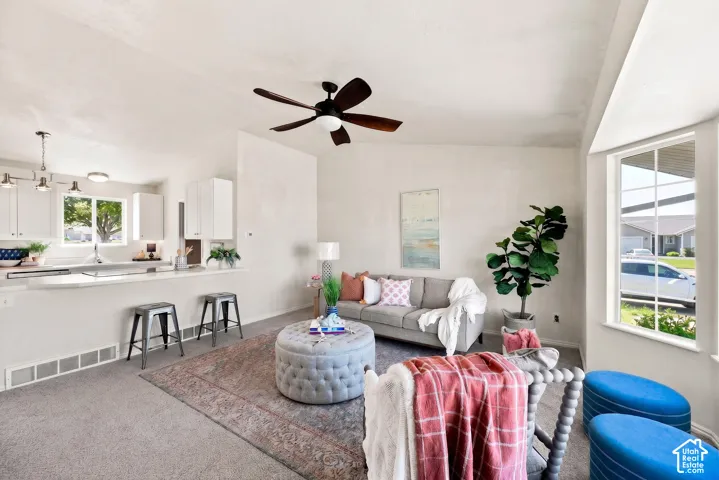 Open-concept living area with vaulted ceilings, large picture window, and a ceiling fan