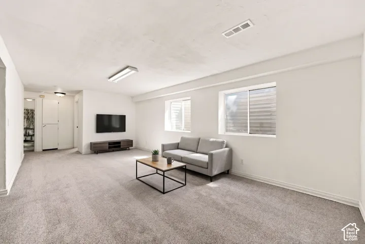 Carpeted living area with white walls, two windows, and overhead lighting,  Virtual display