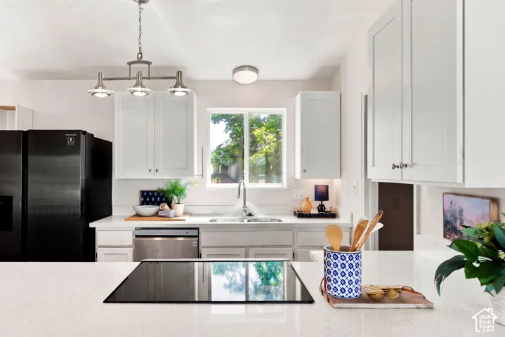 White shaker cabinetry, light-toned countertops, stainless steel appliances, electric cooktop, and undermount sink