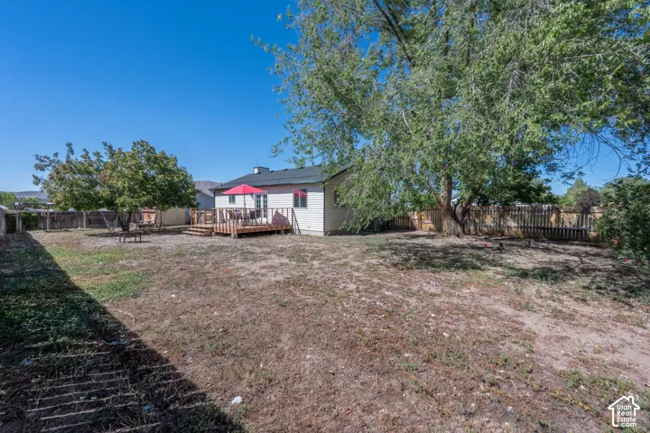 Expansive backyard featuring a wood deck, wood privacy fencing, and mature trees