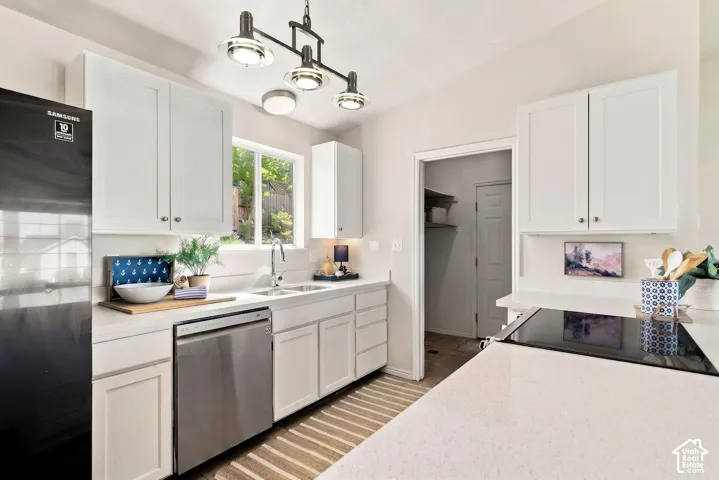 White shaker cabinetry, stainless steel dishwasher, undermount sink, solid surface countertops, and a built-in cooktop