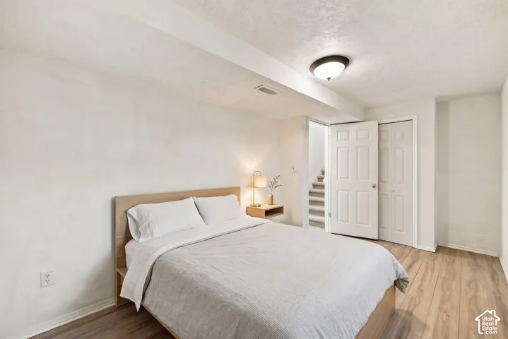 Wood-finish flooring throughout, bright white walls, flush mount ceiling light, and built-in closet with bifold doors. Virtual display