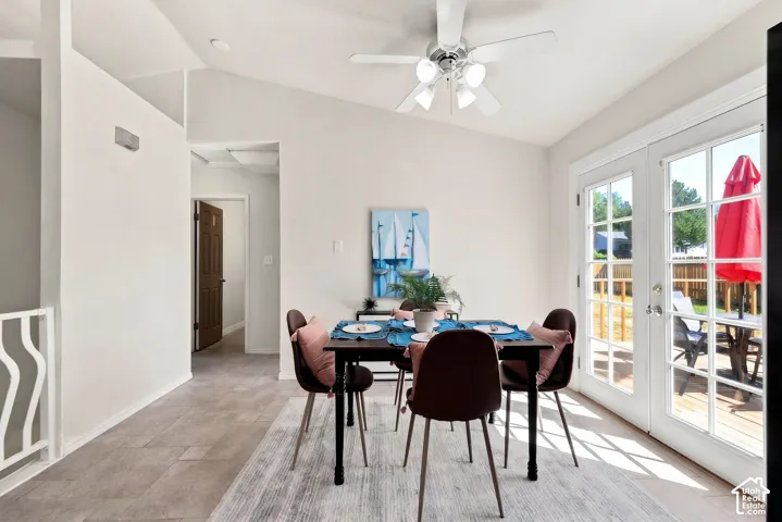 Vaulted ceiling, white ceiling fan with integrated lighting, tile flooring, and double French doors opening to an exterior deck