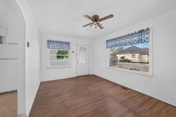 Wood-finish flooring, white walls, and a ceiling fan