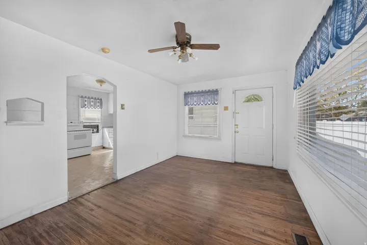 Wood-finish flooring throughout, arched doorway entry, and a ceiling fan with integrated lighting