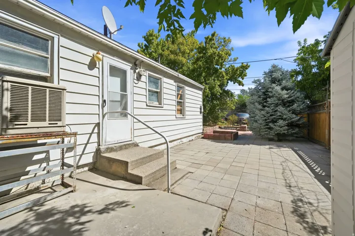 Spacious patio featuring permeable pavers, metal handrails, and mature landscaping with established trees and shrubs