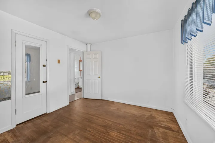 Wood-finish flooring with white walls and a ceiling-mounted light fixture