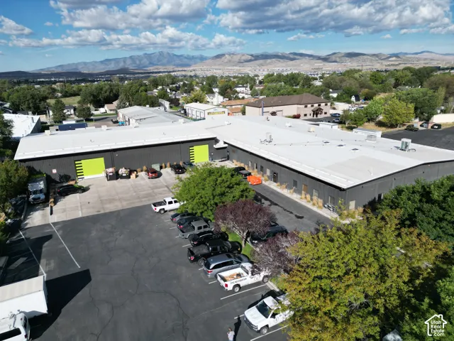 Mountain backdrop, expansive lot, multiple buildings, large paved parking area, mature trees