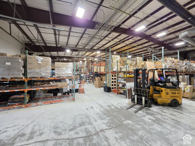 High ceilings with exposed structural beams, extensive overhead lighting, and abundant high-capacity shelving units